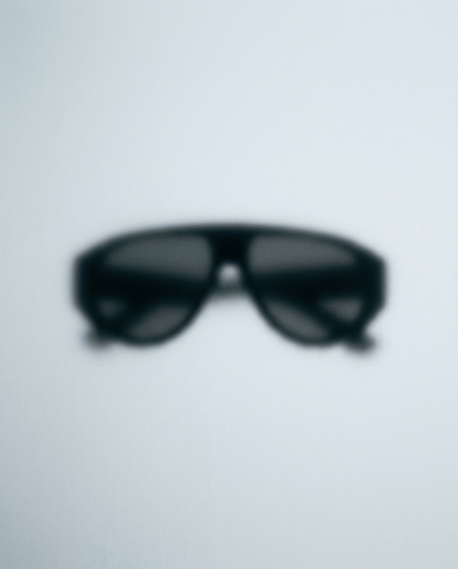 A softly blurred sunglasses silhouette teasing THE ELITE EDIT